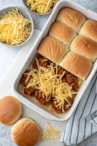 BBQ chicken and cheese layered on slider buns in a baking dish
