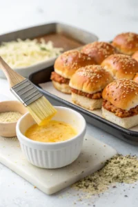 Garlic butter being brushed over the top of slider buns